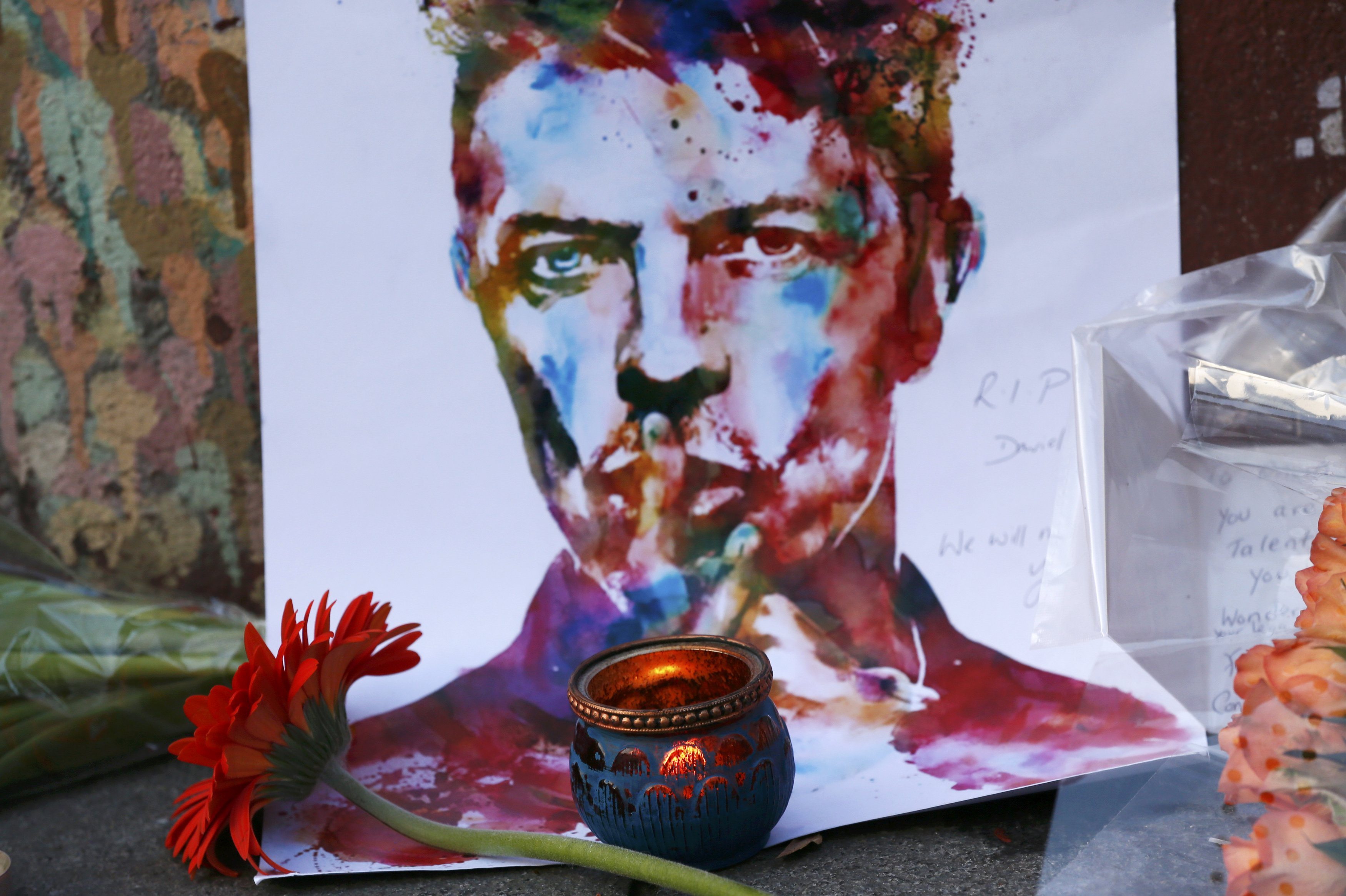 Tributes are seen next to a mural of David Bowie in Brixton, south London, January 11, 2016. David Bowie, a music legend who used daringly androgynous displays of sexuality and glittering costumes to frame legendary rock hits "Ziggy Stardust" and "Space Oddity", has died of cancer. REUTERS/Stefan Wermuth